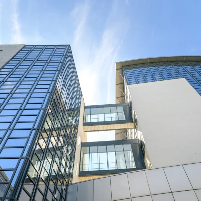 Zwei moderne Bürogebäude mit Glasfassaden und zwei gläsernen Verbindungsbrücken in Schwalbach bei blauem Himmel.