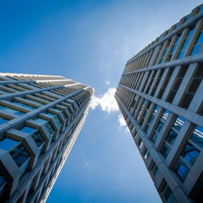 Zwei moderne Hochhäuser mit Glasfassade ragen in den blauen Himmel hinauf.