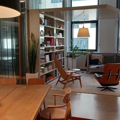 Stilvoll eingerichteter Lounge-Bereich im Frankencampus Nürnberg mit Bücherregal, Sesseln und großer Fensterfront.