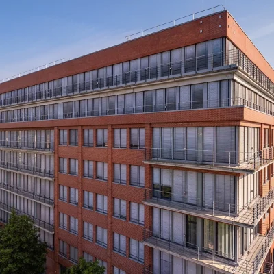 Eckgebäude in Berlin mit roter Fassade, großen Fenstern und Balkonen über mehrere Etagen.