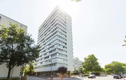 Moderne Außenansicht eines Bürohochhauses an der Adickesallee in Frankfurt mit klarer Fassadenstruktur, reflektierenden Fensterbändern und Sonneneinfall im oberen Gebäudebereich.