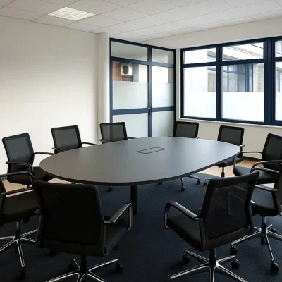 Moderner Besprechungsraum in einem Bürogebäude an der Erkrather Straße in Düsseldorf mit ovalem Konferenztisch, schwarzen Drehstühlen und großen Fensterflächen für Tageslichteinfall.