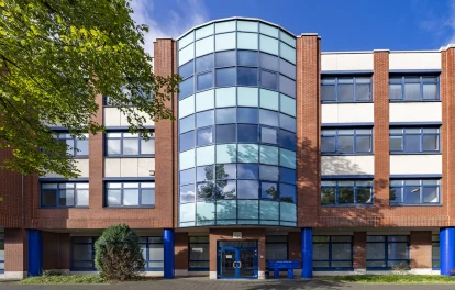 Zentrale Fassadenansicht eines Bürogebäudes an der Erkrather Straße in Düsseldorf mit verglastem Eingangsbereich, symmetrischer Architektur und blau akzentuierten Stützen.