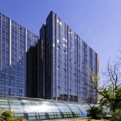 Detailansicht eines Bürohochhauses in der Hollestraße in Essen mit Glasfassade, begrüntem Umfeld und angrenzenden Wegen.