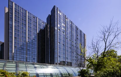 Detailansicht eines Bürohochhauses in der Hollestraße in Essen mit Glasfassade, begrüntem Umfeld und angrenzenden Wegen.