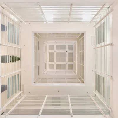 Vertikaler Blick in ein Atrium eines Bürogebäudes in der Marburger Straße in Berlin mit weißer Architektur, Geländern und natürlichem Lichteinfall von oben.