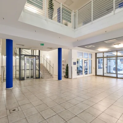 Helles Eingangsfoyer in einem Bürogebäude in der Marburger Straße in Berlin mit automatischen Glastüren, offener Raumstruktur und direktem Zugang zum Außenbereich.