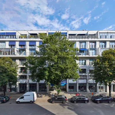 Straßenansicht eines mehrgeschossigen Büro- und Geschäftshauses in der Marburger Straße in Berlin mit Balkonen, großen Fensterflächen und baumbestandener Straße.