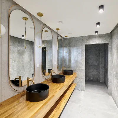 Modern gestalteter Sanitärbereich in einem Bürogebäude in der Soorstraße in Berlin mit hochwertigen Materialien, Holzwaschtisch, schwarzen Aufsatzbecken und dekorativen Spiegeln.