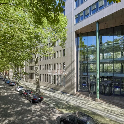 Straßenansicht eines Bürogebäudes in der Soorstraße in Berlin mit repräsentativem Eingangsbereich, baumbestandener Allee und parkenden Fahrzeugen entlang der Straße.
