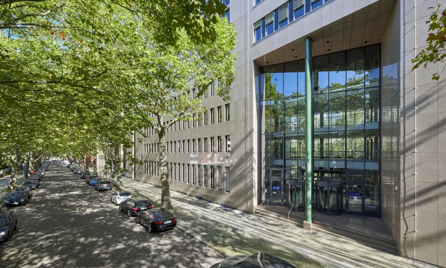 Straßenansicht eines Bürogebäudes in der Soorstraße in Berlin mit repräsentativem Eingangsbereich, baumbestandener Allee und parkenden Fahrzeugen entlang der Straße.