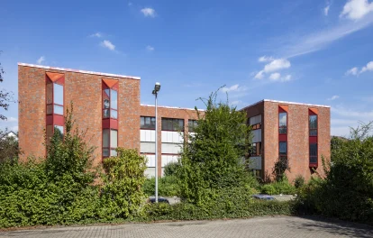 Außenansicht des Büroensembles Alter Hellweg 56–60 in Dortmund mit roter Klinkerfassade, markanten Fensterachsen und großzügiger Begrünung im Vordergrund.