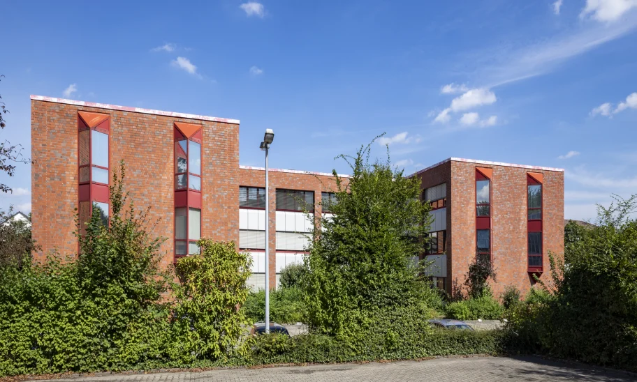 Außenansicht des Büroensembles Alter Hellweg 56–60 in Dortmund mit roter Klinkerfassade, markanten Fensterachsen und großzügiger Begrünung im Vordergrund.