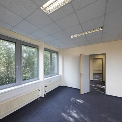Helle Bürofläche mit großen Fenstern, Blick ins Grüne, Teppichboden und abgehängter Decke mit integrierter Beleuchtung im Objekt Alter Hellweg 56–60 in Dortmund.
