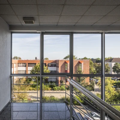 Treppenhaus am Alten Hellweg 56–60 in Dortmund mit großer Fensterfront, Tageslichteinfall und Blick auf die Außenanlagen.