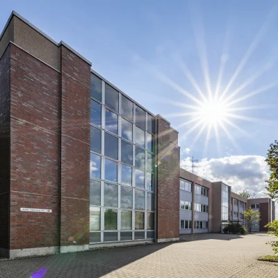 Außenansicht der Bürogebäude am Alten Hellweg 56–60 in Dortmund bei Sonnenschein mit Backsteinfassade und begrüntem Umfeld.
