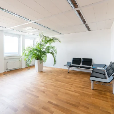 Moderner Empfangs- und Wartebereich mit Sitzgelegenheiten, Holzfußboden und zeitgemäßer Beleuchtung im Bürogebäude Karl-Wiechert-Allee 18–22 in Hannover.