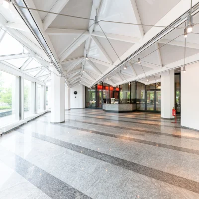 Großzügiger, lichtdurchfluteter Lichthof mit Glasdach, Natursteinboden und moderner Architektur im Bürogebäude Karl-Wiechert-Allee 5 in Hannover.