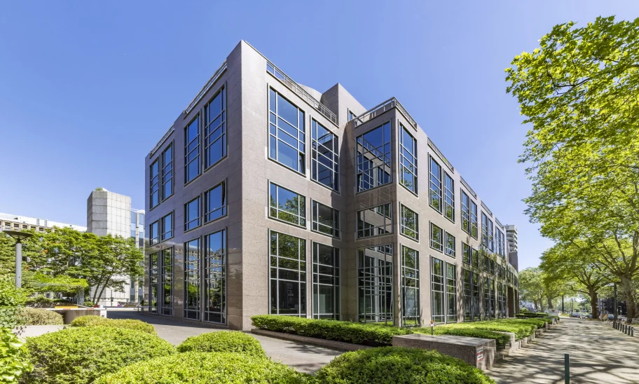 Eckansicht eines hochwertigen Bürogebäudes mit Natursteinfassade und großzügigen Fensterflächen an der Kaiserswerther Straße in Düsseldorf.