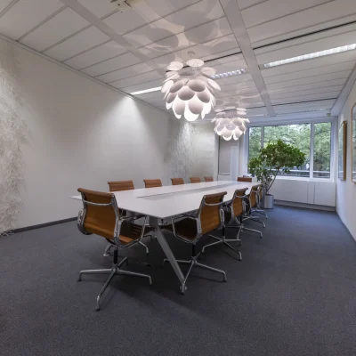 Eleganter Besprechungsraum mit großem Tisch, Designpendelleuchten und Tageslicht im Bürogebäude an der Kaiserswerther Straße in Düsseldorf.