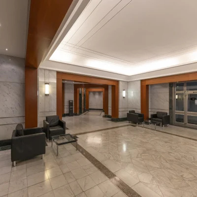 Repräsentative Lobby mit Natursteinboden, Holzverkleidungen, Sitzgelegenheiten und indirekter Beleuchtung im Bürogebäude an der Kaiserswerther Straße in Düsseldorf.