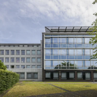 Außenansicht des Bürogebäudes Nördlicher Zubringer in Düsseldorf mit moderner Glasfassade, klarer Architektur und begrüntem Außenbereich.