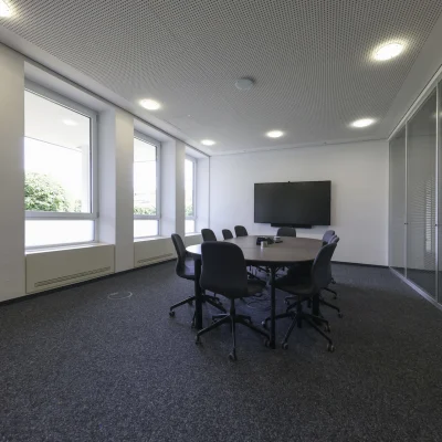 Heller Besprechungsraum im Objekt Nördlicher Zubringer in Düsseldorf mit großem Konferenztisch, moderner Beleuchtung, Akustikdecke und großzügigen Fensterflächen für angenehmes Tageslicht.