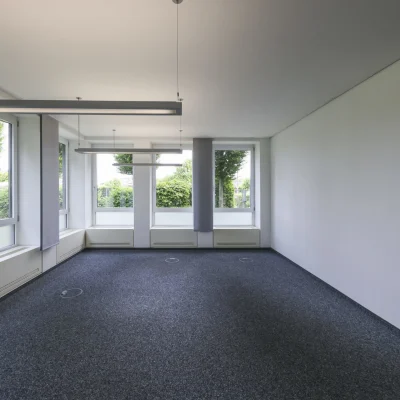 Flexible Bürofläche im Objekt Nördlicher Zubringer in Düsseldorf mit bodentiefen Fenstern, moderner Pendelbeleuchtung, neutralem Bodenbelag und vielseitigen Nutzungsmöglichkeiten für unterschiedliche Arbeitskonzepte.