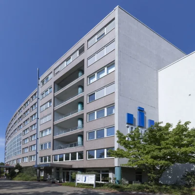 Gesamtansicht des TRIGA Bürocenters mit Vorplatz, Fahnenmasten und exponierter Lage an einer zentralen Verkehrsachse Hannovers.
