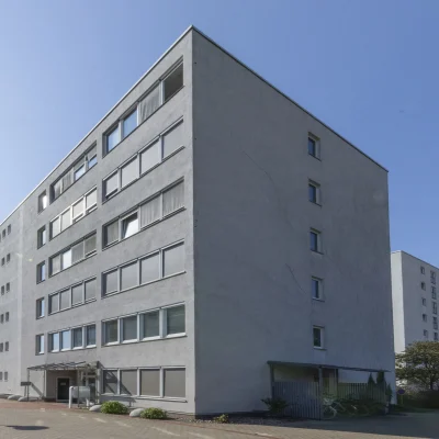 Längsansicht des Bürogebäudes mit regelmäßig angeordneten Fensterflächen und begrünter Umgebung im Stadtteil Groß-Buchholz.
