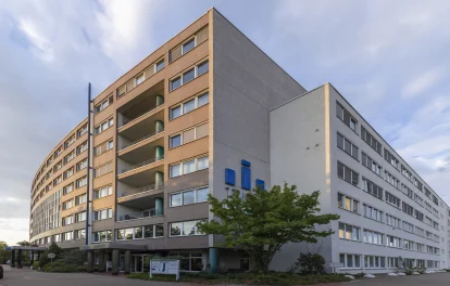 Eckansicht des TRIGA Bürocenters mit klarer Fassadengliederung, zurückspringenden Gebäudeteilen und urbanem Umfeld.
