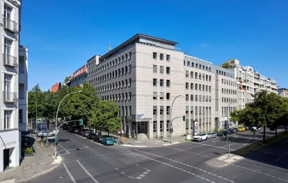 Moderne Außenansicht des Bürogebäudes Uhlandeck in Berlin mit Ecklage an einer belebten Straßenkreuzung und urbanem Umfeld.