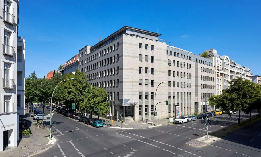Moderne Außenansicht des Bürogebäudes Uhlandeck in Berlin mit Ecklage an einer belebten Straßenkreuzung und urbanem Umfeld.