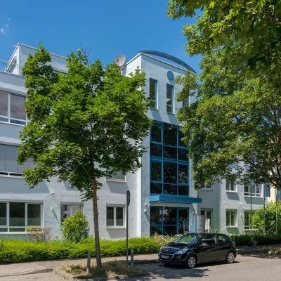 Außenansicht des Gebäudes Kreuzberger Ring 68 in Wiesbaden mit blauer Fensterfront am Eingang von der gegenüberliegenden Straßenseite aus.
