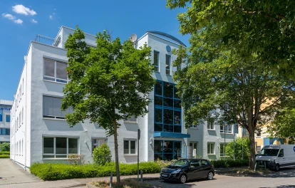 Außenansicht des Gebäudes Kreuzberger Ring 68 in Wiesbaden mit blauer Fensterfront am Eingang von der gegenüberliegenden Straßenseite aus.