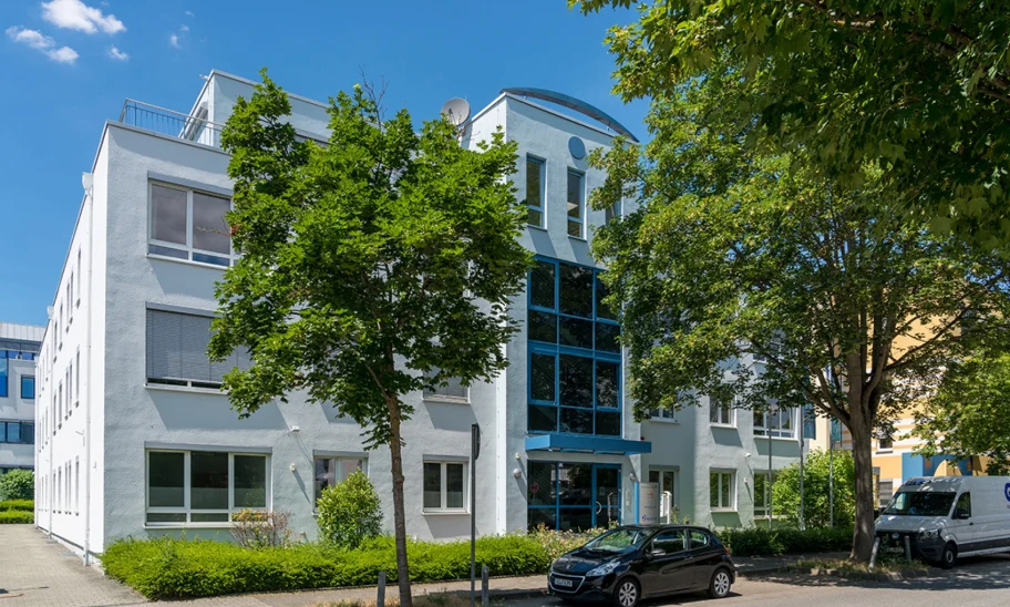 Außenansicht des Gebäudes Kreuzberger Ring 68 in Wiesbaden mit blauer Fensterfront am Eingang von der gegenüberliegenden Straßenseite aus.