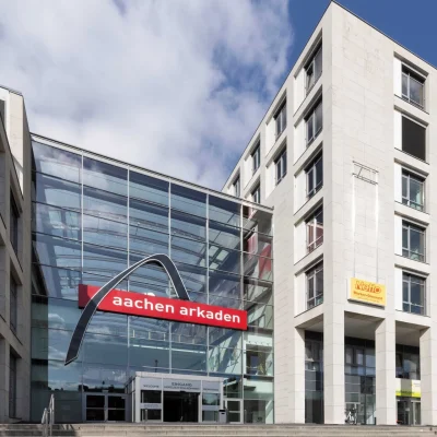 Außenansicht der Aachen Arcaden mit moderner Architektur, Büro- und Einzelhandelsflächen an einer zentralen Verkehrsachse.