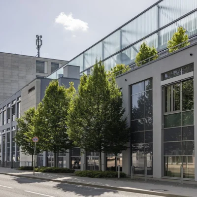 Fassadenansicht der Aachen Arcaden mit großzügigen Fensterflächen und vorgelagerter Baumreihe.