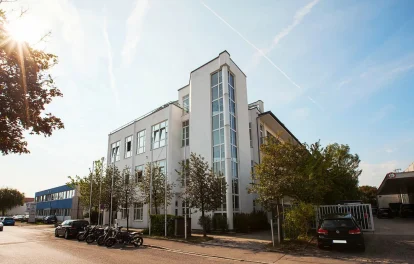 Außenansicht des Gutenberg Centers in München mit moderner Büroimmobilie, heller Fassade, großen Fenstern und begrüntem Umfeld.