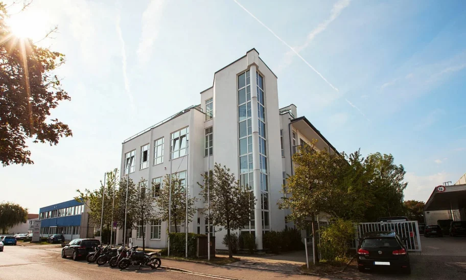 Außenansicht des Gutenberg Centers in München mit moderner Büroimmobilie, heller Fassade, großen Fenstern und begrüntem Umfeld.