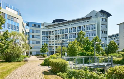 Eingangsbereich eines Bürogebäudes mit Treppe und Grünanlagen