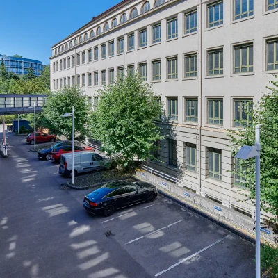 Innenhof mit Besucherparkplätzen, Verbindungsbrücke und Bestandsgebäuden