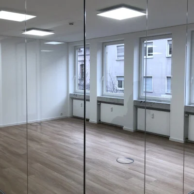 Leere, moderne Bürofläche mit bodentiefen Glaswänden, Holzoptikboden und großformatigen Fenstern in der Antoniterstraße 33 in Frankfurt.