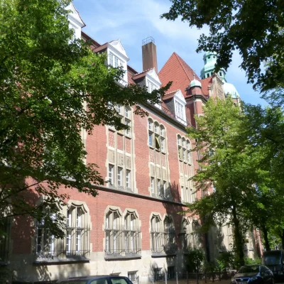 Frontale Außenansicht des historischen Gebäudes in der Bergstraße 1 in Berlin mit roter Backsteinfassade und prägnantem Kuppelturm.