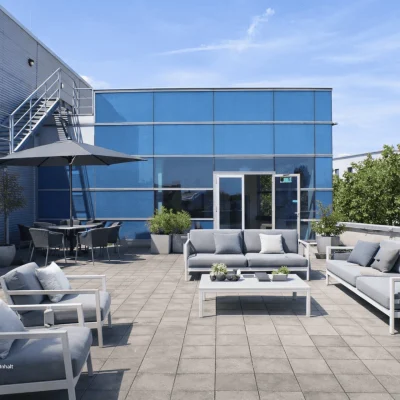 Großzügige Dachterrasse mit Sitzgelegenheiten, Begrünung und moderner Gebäudefassade als attraktiver Aufenthaltsbereich der Immobilie in der Berliner Straße 206–216 in Offenbach am Main.
