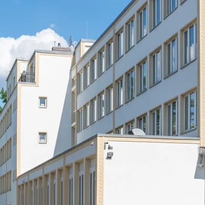 Außenansicht der Büroimmobilie Heerstraße 24 in Berlin mit heller Fassade, zahlreichen Fenstern und blauem Himmel.