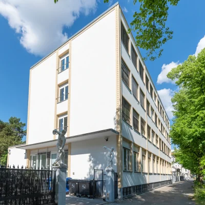 Straßenansicht der Büroimmobilie Heerstraße 24 in Berlin mit heller Fassade und grünen Bäumen bei sonnigem Wetter.
