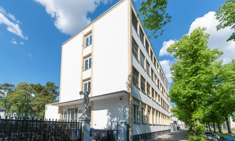 Straßenansicht der Büroimmobilie Heerstraße 24 in Berlin mit heller Fassade und grünen Bäumen bei sonnigem Wetter.