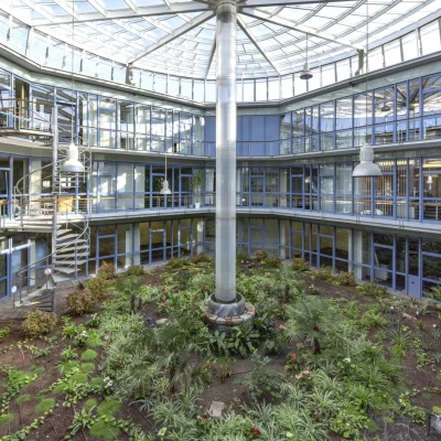 Atrium mit gläserner Kuppel, Wendeltreppe und üppig bepflanztem Innenhof aus der Vogelperspektive