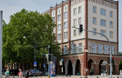Historisches Backsteingebäude mit Arkadengang und Staffelgiebel an einer Straßenkreuzung